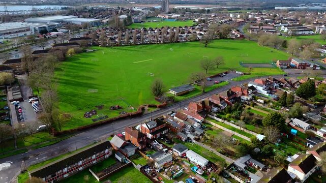 aerial drone shot high angle over the Millbrook suburban housing area estate in Southampton at sunset with trees, homes and nature surrounding. Shot in winter with traffic and cars driving the streets