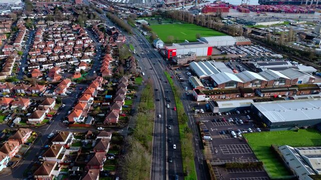 aerial drone shot high angle over the Millbrook suburban housing area estate in Southampton at sunset with trees, homes and nature surrounding. Shot in winter with traffic and cars driving the streets