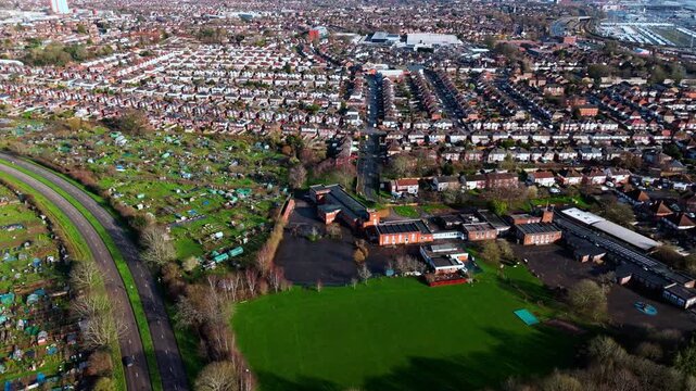 aerial drone shot high angle over the Millbrook suburban housing area estate in Southampton at sunset with trees, homes and nature surrounding. Shot in winter with traffic and cars driving the streets