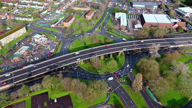 aerial Birds Eye overhead shot over the Millbrook flyover roundabout in Southampton, Hampshire, England. Shot at sunset in winter with bright light shining as the cars pass over the industrial suburb.