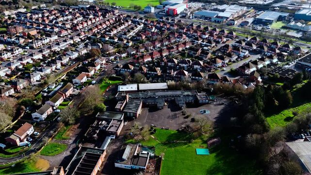 aerial drone shot high angle over the Millbrook suburban housing area estate in Southampton at sunset with trees, homes and nature surrounding. Shot in winter with traffic and cars driving the streets