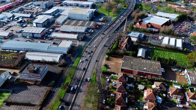 aerial drone shot high angle over the Millbrook suburban housing area estate in Southampton at sunset with trees, homes and nature surrounding. Shot in winter with traffic and cars driving the streets