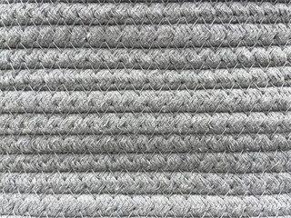 Close-up of grey braided rope textile texture arranged in horizontal rows. Detailed woven cord...