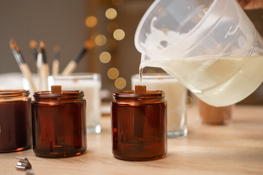 Concept of creative hobby and handmade candles. female hands pouring melted soy wax into jar.