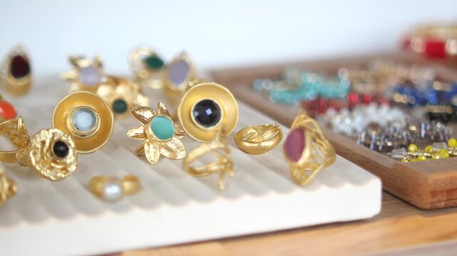 Close up of luxury gold rings with colorful gemstones on white display tray at jewelry boutique store