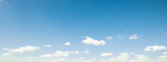 the sky is clear blue with fluffy white clouds, the sky is very bright, and the sun shines.