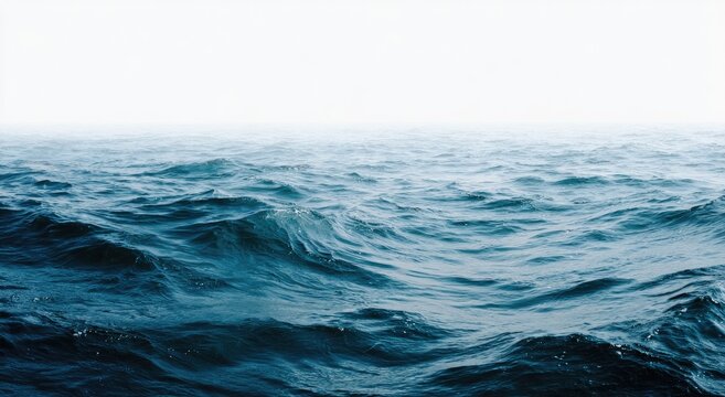 An expanse of ocean waves in varying shades of blue, blending into a hazy white sky