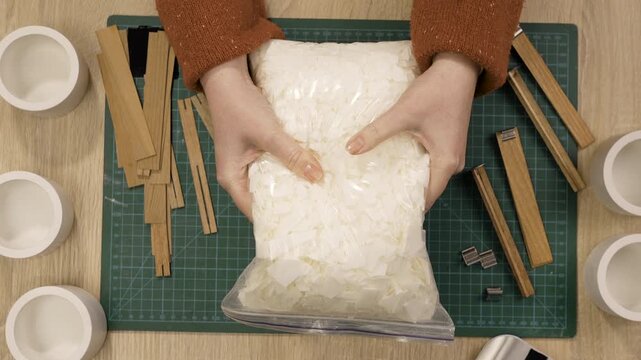 Female hands holding package with wax flakes for crafting handmade candles