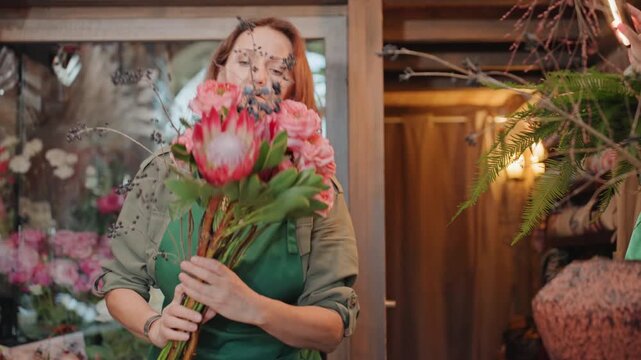Flower arrangement process. Woman skillfully assembles floral display. Careful woman arranges protea with detailed attention. Flower artist precisely cuts stems and adorns protea blossoms beautifully