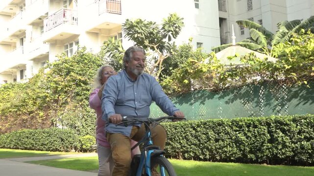 Retired Active senior indian couple riding bicycle together, freedom and adventurous spirit in 60s. Healthy fit Elderly husband wife enjoy Retirement life. Fitness and vitality. 4k