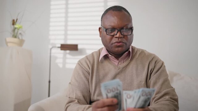 Financial success and wealth, portrait of average african american man with cash . Winner of lottery enjoying his winnings and counting new dollars banknotes, save money and rejoicing by savings