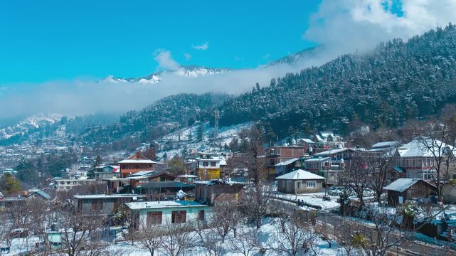 4K Timelapse of the small village in Himalaya mountains in winter. Clouds moving over snow mountains during sunny day. Manali after fresh snowfall. Theme of travel and nature. Winter scenery of cold w
