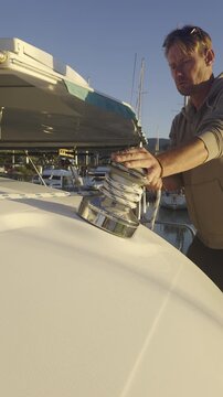 Professional sailor operating a winch on a white yacht at golden hour