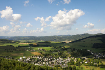 Rolling hills landscape with mountains, nature and small town city view on summer day.