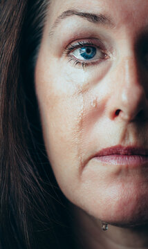 Close up of half of woman's face with tears running down her cheeks.