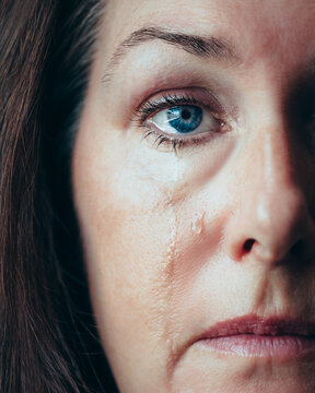 Close up of half of woman's face with tears running down her cheeks.