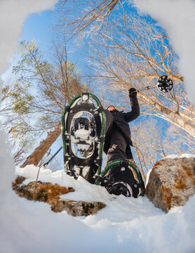 Person snowshoeing on sunny winter day shot from below.