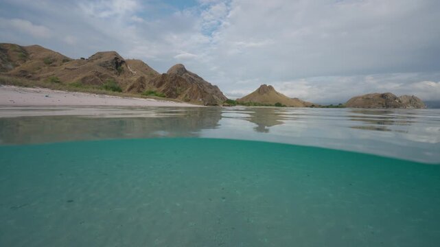 Dramatic split shot at the beach in the Komodo National Park contrasting the underwater world with the mountainous terrain on the beach