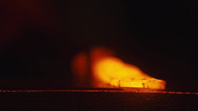 A black smith forging a sword in a darkroom.