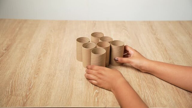 Close-up footage of hands arranging small paper rolls and cutting one piece to begin a handmade craft project. The video shows the preparation process and careful manual work in a creative workspace.