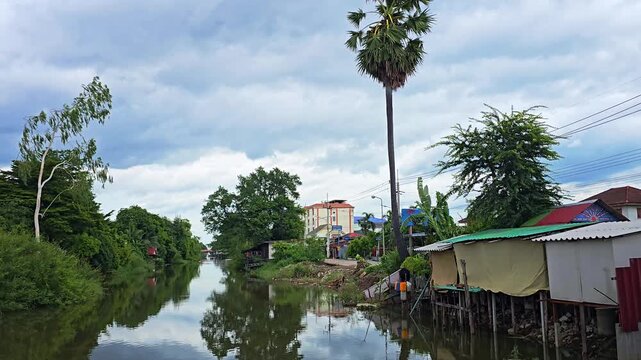 Scenic View of Khlong 4 Canal in Lam Luk Ka, Pathum Thani, Thailand with Traditional Wooden Shacks Along the Waterway