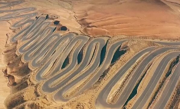 A dramatic mountain road twisting through the Pamir Plateau with countless sharp hairpin turns carved into high Xinjiang terrain.