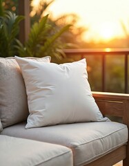 Fototapeta premium Soft white cushion rests on outdoor furniture on a warm sunset. Gentle light creates cozy ambiance on patio. Relaxing evening on balcony with view.