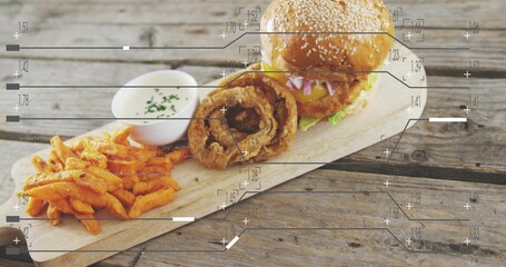 Displaying sesame-seed cheeseburger, onion rings, sweet-potato fries and ramekin on weathered board © vectorfusionart