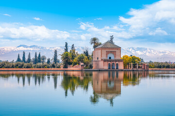 Menara Gardens pavilion reflecting in tranquil waters with snow-capped Atlas Mountains, Marrakech, Morocco