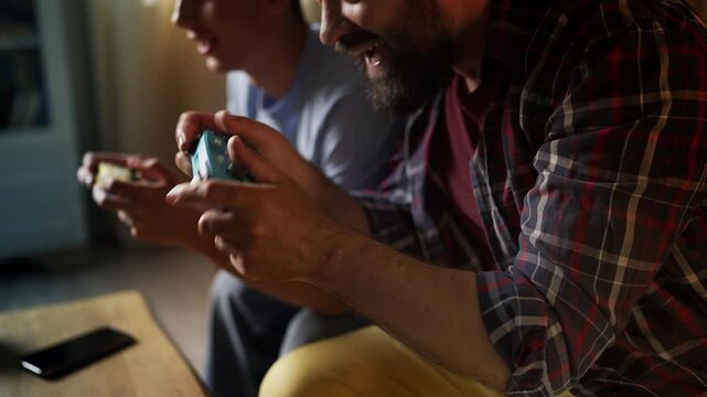 Middle-aged man competing with his teen son in a video game, family pastime