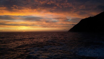 Fototapeta premium devastating and spectacular sea storm in Framura, Liguria, Cinque Terre - sea waves crash on the rocks of the coast creating an explosion of water - fiery sunset and white splashes of water