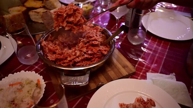 Woman serving farfalle pasta at a dinner party