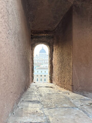 Obraz premium St. Peter's Basilica viewed through a narrow ancient stone window in Rome at sunset.
