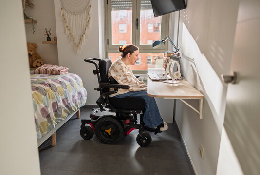 Young woman using electric wheelchair working from home