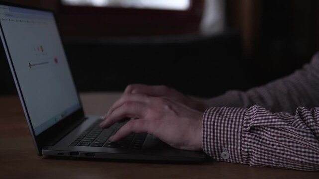 Male Evaluates App Interface. Caucasian Male Explores Software Features On Laptop. Man From Caucasian Descent Conducts Usability Test With Prototype On His Laptop In Dim Lighting