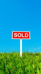 Sold sign in green grass against blue sky real estate success concept low angle view outdoor environment