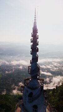 Cinematic aerial view of Ambuluwawa Tower in Kandy &ndash; Iconic white spiral architecture rising above misty mountains in Sri Lanka