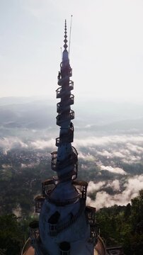 Cinematic aerial view of Ambuluwawa Tower in Kandy &ndash; Iconic white spiral architecture rising above misty mountains in Sri Lanka
