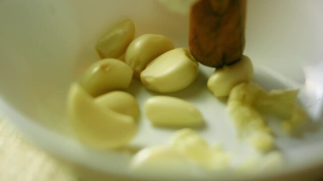 Person is squeezing the peeled garlic cloves in a bowl