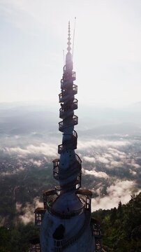 Cinematic aerial view of Ambuluwawa Tower in Kandy &ndash; Iconic white spiral architecture rising above misty mountains in Sri Lanka