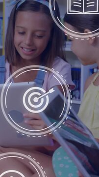 Vertical video: Children sitting on library floor tapping tablets, launching UI icons for learning