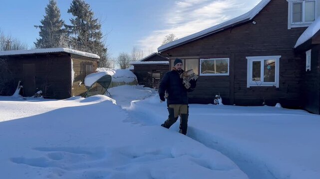 The guy carries firewood from the wood firebox for the barbecue. A country house is visible in the background. Horizontal video.