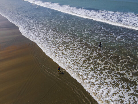 Cox's Bazar, Bangladesh - 16 May 2024: Aerial view of where the golden sands meet the turquoise sea, as frothy waves gently lap the shore, and figures dot the expansive beach.