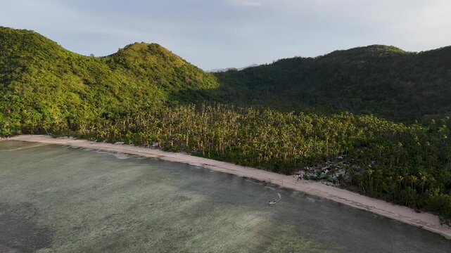 Drone aerial view of Bayang Basecamp or Calibangbangan Camp and turquoise reef along Calibangbangan Island coastline between Coron and El Nido, Palawan, Philippines.