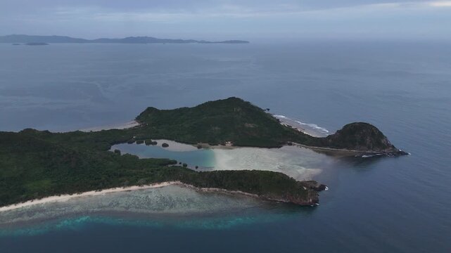 Drone aerial view of Bayang Basecamp or Calibangbangan Camp and turquoise reef along Calibangbangan Island coastline between Coron and El Nido, Palawan, Philippines.