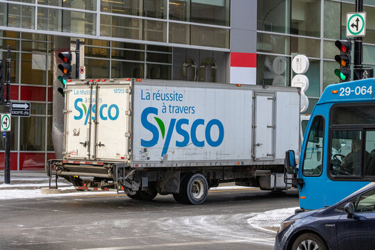 Canada, Montreal, 22 December 2025 : Sysco delivery truck beside blue city bus and signage