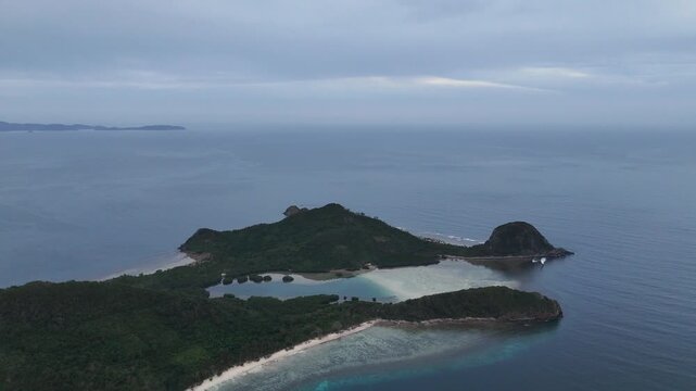 Drone aerial view of Bayang Basecamp or Calibangbangan Camp and turquoise reef along Calibangbangan Island coastline between Coron and El Nido, Palawan, Philippines.
