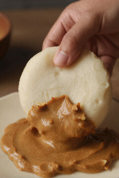 Hand dipping fufu into peanut sauce