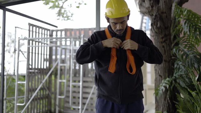 Worker Fastening Harness In The Work Site, A focused worker securing a safety harness on site, highlighting professional safety standards, perfect for industrial, safety awareness and documentary.