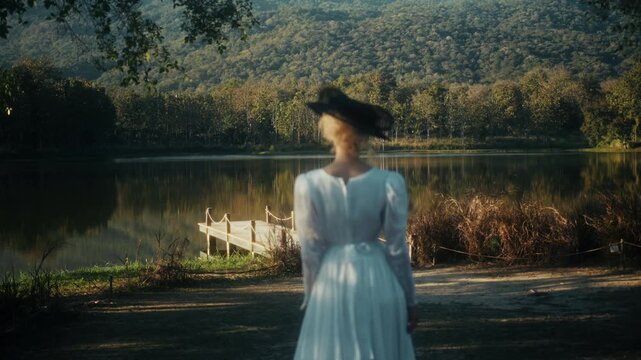 Traveler Wears Sunhat. Casual Explorer Adjusting Her Hat Amid Glowing Sunshine On Gentle Grassy Slope